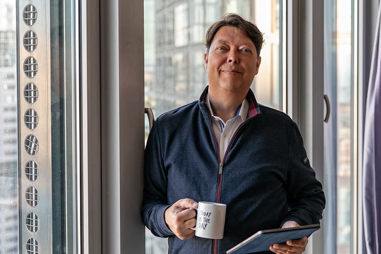 Consultant leaning by a window holding a coffee cup with the text Today is the Day